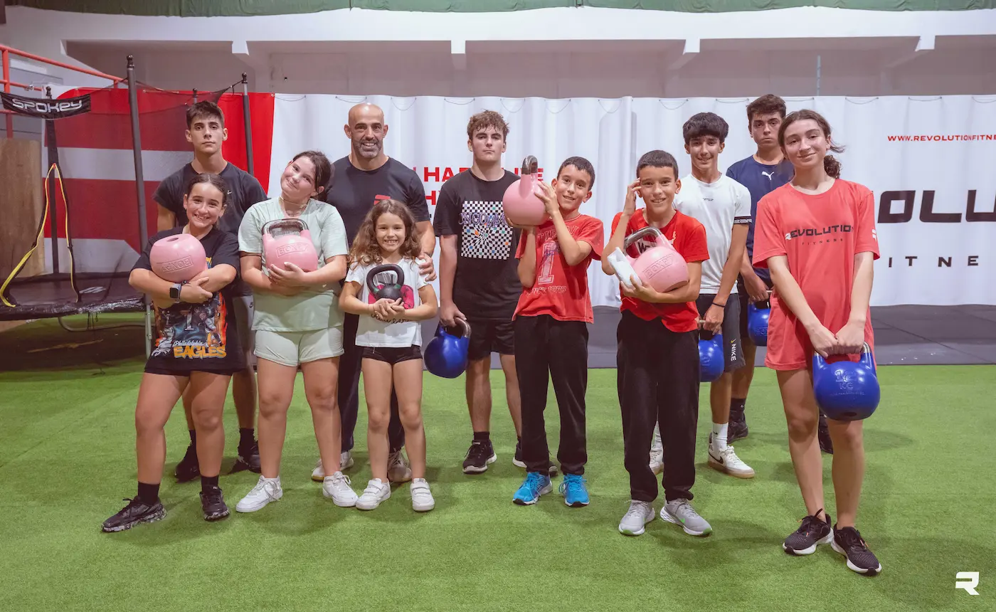 Turma de CrossFit Kids e Teens com o treinador Luís Sá Bastardo a segurar kettlebells no ginásio Revolution Fitness na Figueira da Foz